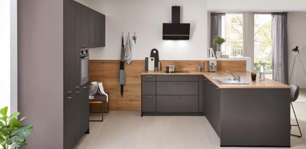 Moderne Nobilia Küche in dunklen Fronten mit warmen Holzarbeitsflächen, funktionale L-Form mit integriertem Essbereich, klare Linien und zeitloses Design für den Alltag.