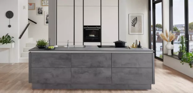 Minimalistische Nobilia Designküche mit großzügiger Kochinsel in Betonoptik, helle Hochschrankwand und offene Raumgestaltung, stilvoll und modern mit urbanem Charakter.
