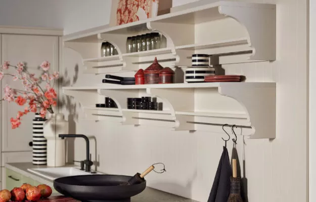 Liebevoll gestaltetes Küchen-Detail im Landhausstil von Nolte mit offenen Regalen, dekorativen Konsolen und warmen, hellen Farbtönen. Die Kombination aus klassischen Formen, modernen Armaturen und stilvollen Accessoires schafft eine wohnliche, charmante Küchenatmosphäre.